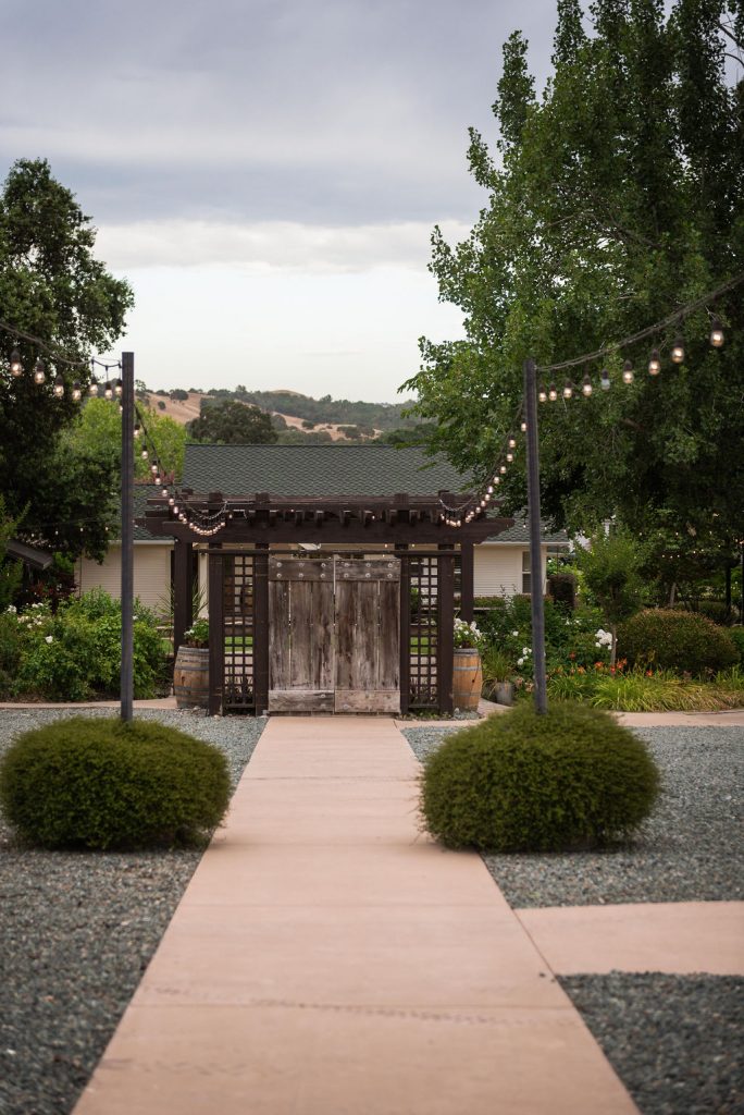 Rancho Victoria Weddings. Amador County. Dinner tables with market lights set up on large patio. Looking toward the divider doors to separate ceremony.