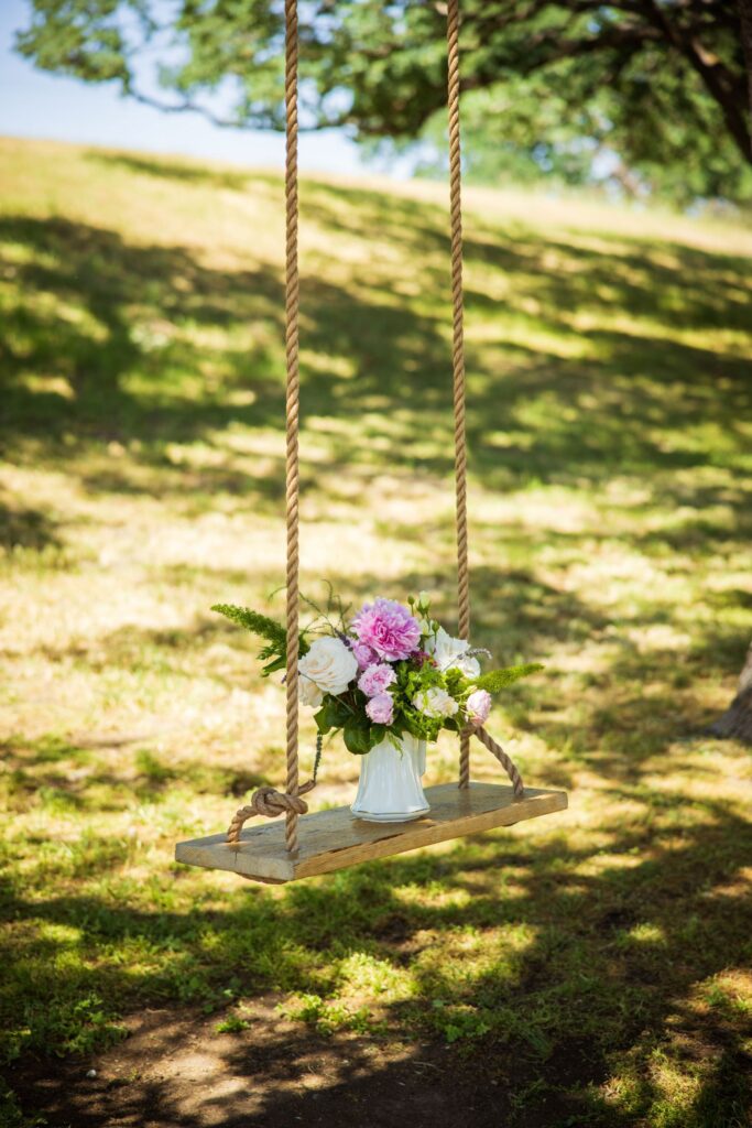 Crossing at Thomes Creek Wedding Events, Corning. Hanging swing with pitcher of flowers.